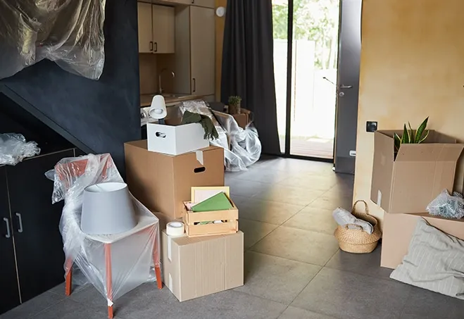 Wohnraum während der Entrümpelung: gestapelte Kartons, abgedeckte Möbel und verpackter Hausrat