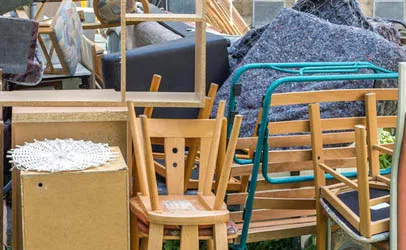 Aussortierte Möbel, Sessel und ein aufgerollter Teppich vor der Abholung durch die Entrümpelungsfirma
